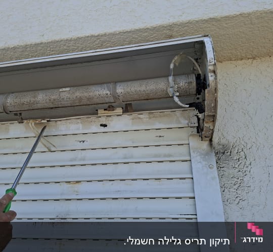 תיקון תריס גלילה עם מברג על קיר חיצוני